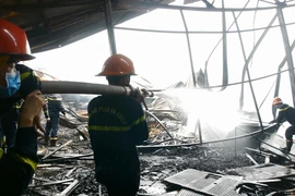 Các chiến sỹ cảnh sát Phòng cháy chữa cháy đang tích cực dập tắt khu vực còn cháy âm ỉ bên trong. (Ảnh: Quốc Dũng/- TTXVN)