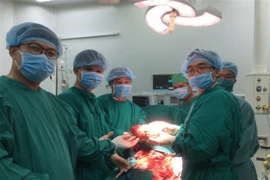 Các bác sỹ lấy khối u khỏi cơ thể bệnh nhân. (Ảnh: Ánh Tuyết/TTXVN)