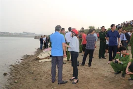 Thi thể được đưa lên bờ, chờ người nhà đến nhận diện. (Ảnh: Nhan Sinh/TTXVN)