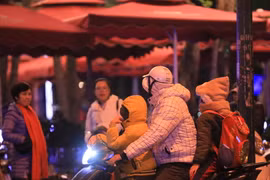 Một gia đình đã trang bị đồ ấm cho trẻ nhỏ khi phải di chuyển ngoài đường lúc 22h. (Ảnh: Hoàng Hiếu/TTXVN)
