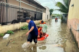 Cán bộ, chiến sỹ Ban Chỉ huy Quân sự thành phố Phú Quốc, tỉnh Kiên Giang, cùng với lực lượng địa phương ứng cứu, sơ tán người dân đến nơi an toàn do mưa lớn gây ngập cục bộ trên đảo. (Ảnh: TTXVN phát)