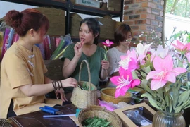 Thanh Nhàn (áo xanh) đang giao tiếp với các bạn khuyết tật bằng ngôn ngữ ký hiệu. (Ảnh: Tường Vi/TTXVN)