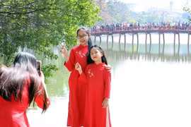 Người dân ghi lại hình ảnh đẹp bên cầu Thê Húc, quận Hoàn Kiếm, trong mùng 2 Tết. (Ảnh: Phạm Kiên/TTXVN)