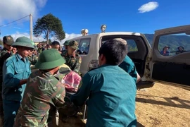 Lực lượng chức năng đưa thi thể nạn nhân ra ngoài. (Ảnh: TTXVN phát)