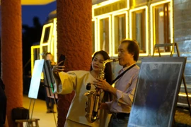 Du khách thích thú với màn trình diễn saxophone tại sân ga Đà Lạt trước giờ tàu hỏa khởi hành. (Ảnh: Nguyễn Dũng/TTXVN)