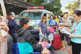 Thân nhân và bệnh nhi chờ đợi để lên chuyến xe 0 đồng về quê đón Tết. (Ảnh: Đinh Hằng/TTXVN)