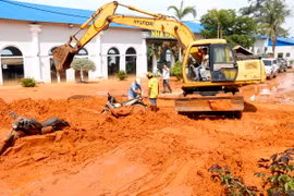 Người dân cùng tham gia cào cát và di chuyển xe máy bị vùi lấp ra ngoài. (Ảnh: Nguyễn Thanh/TTXVN)