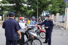 Lực lượng chức năng kiểm tra phiếu tại cổng chợ (Ảnh: Hoàng Đạt/Vietnam+)