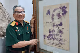 Họa sỹ Lê Duy Ứng và phiên bản của bức chân dung Bác Hồ vẽ bằng máu. (Ảnh: Minh Thu/Vietnam+)