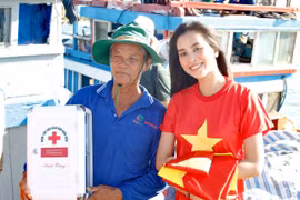 Hoa hậu Tiểu Vi trao cờ và tủ thuốc cho 1 chủ tàu. (Ảnh: Tùng Lâm/Vietnam+)