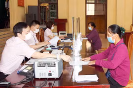 Các đối tượng chính sách ở xã Phù Linh, huyện Sóc Sơn (Hà Nội) đến Điểm giao dịch của Ngân hàng Chính sách xã hội tại trụ sở UBND xã làm thủ tục, nhận vốn vay.