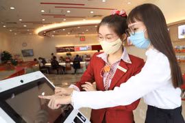 Khách hàng sử dụng Smart Kiosk tại HDBank. (Ảnh: Vietnam+)