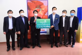 Lãnh đạo Vietcombank trao biển tài trợ 01 máy xét nghiệm COVID-19 cho tỉnh Hải Dương. (Ảnh: Vietnam+)