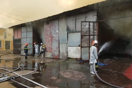 Cảnh sát tiếp tục phun nước vào hiện trường, chống cháy lan (Ảnh: Minh Sơn/Vietnam+) 