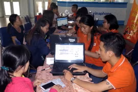 Nhân viên Công ty FPT hỗ trợ người dân truy cập Internet đặt mua vé tàu Tết Đinh Dậu 2017 tại ga Sài Gòn. )Ảnh: Hoàng Hải/TTXVN)