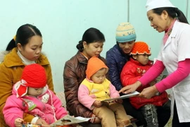 Nhân viên y tế hướng dẫn cách chăm sóc trẻ em khi trời trở rét. (Ảnh: Dương Ngọc/TTXVN)