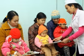 Nhân viên y tế hướng dẫn cách chăm sóc trẻ em khi trời trở rét. (Ảnh: Dương Ngọc/TTXVN)