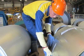 Công nhân đang đóng gói thành phẩm thép mạ. (Ảnh: Hồng Nhung/TTXVN)