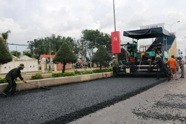 Các đơn vị thi công thảm lại nhựa mặt đường. (Ảnh: Dương Chí Tưởng/TTXVN)