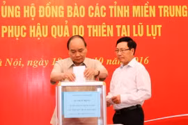 Thủ tướng Nguyễn Xuân Phúc và Phó Thủ tướng, Bộ trưởng Ngoại giao Phạm Bình Minh quyên góp ủng hộ đồng bào các tỉnh miền Trung khắc phục hậu quả do thiên tai lũ lụt. (Ảnh: Thống Nhất/TTXVN)