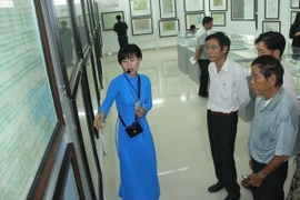 Du khách đến tham quan, tìm hiểu về các hiện vật, bản đồ trưng bày tại triển lãm. (Ảnh: Bùi Như Trường Giang/TTXVN)