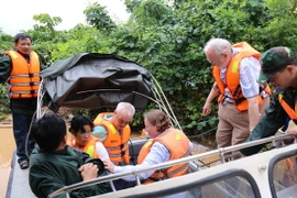 Hành khách của tàu SE19 bị mắc kẹt được đưa lên canô ra nơi an toàn. (Ảnh: Đức Thọ/TTXVN)