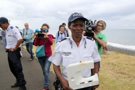 Cảnh sát Pháp với tấm nhựa vừa phát hiện trên đảo Reunion ngày 4/8. (Nguồn: AFP/TTXVN)