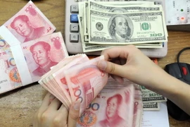 Kiểm tiền nhân dân tệ và USD tại ngân hàng ở tỉnh An Huy, Trung Quốc. (Nguồn: AFP/TTXVN)