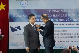 Ông Vincent Floreani gắn Huân chương Cành cọ Hàn lâm cho phó giáo sư-tiến sỹ Nguyễn Ngọc Điện. (Ảnh: Thu Hoài/TTXVN)