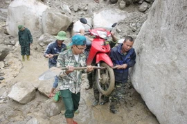 Cán bộ, chiến sỹ tham gia vận chuyển phương tiện giao thông giúp dân qua những đoạn đường bị sạt lở mất đường do mưa lũ. (Ảnh: TTXVN phát)