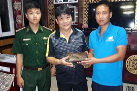 Thuyền trưởng Đinh Khắc Thương (áo xanh, bên phải) trả lại ví tiền cho du khách. (Ảnh: TTXVN phát)