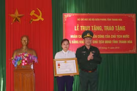 Vợ thiếu tá Vi Văn Nhất đón nhận Huân chương Chiến công hạng Nhất. (Ảnh: Trịnh Duy Hưng- TTXVN)