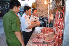 Lực lượng chức năng kiểm tra buôn bán thịt lợn tại các chợ xã. (Ảnh: Huỳnh Phúc Hậu/TTXVN)