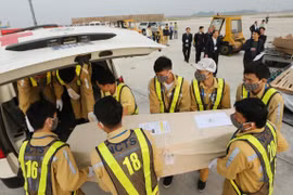 Nhân viên sân bay quốc tế Nội Bài vận chuyển thi thể các nạn nhân lên ô tô để đưa về quê nhà. (Ảnh: Lâm Khánh/TTXVN)