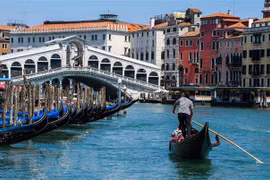 Khách du lịch đi thuyền gondola tại Venice, Ital. (Ảnh: AFP/ TTXVN)