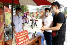 Du khách thực hiện kiểm tra thân nhiệt trước khi vào dâng lễ tại đền Bảo Hà. (Ảnh: Quốc Khánh - TTXVN) 