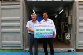 Đại diện Viện Khoa học và Công nghệ Việt Nam-Hàn Quốc bàn giao bảng tượng trưng máy lọc nước cho Trường Dân tộc nội trú THCS huyện Trần Đề. (Ảnh: Tuấn Phi/TTXVN)