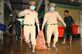 Cán bộ chiên sỹ Công an huyện Thanh Chương hỗ trợ người dân vệ sinh môi trường sau lũ. (Ảnh: Tá Chuyên/TTXVN)