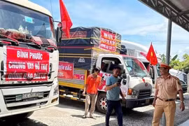 Cán bộ, chiến sĩ Cảnh sát giao thông Trạm Đức Phổ hỗ trợ người và phương tiện vận chuyển hàng cứu trợ dùng cơm miễn phí. (Ảnh: TTXVN)