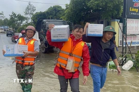 Các lực lượng chức năng và người dân chuẩn bị lương thực hỗ trợ bà con vùng ngập lụt. (Ảnh: Thanh Thuỷ/TTXVN)