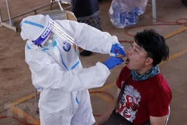 Bác sỹ đang lấy mẫu xét nghiệm cho một người dân Vientiane. (Ảnh: Phạm Kiên/TTXVN) 