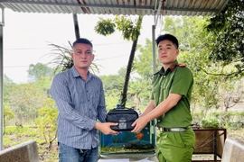 Hạ sỹ Đặng Toàn Tiến, trao trả lại túi đồ bị bỏ quên cho chủ sở hữu. (Ảnh: TTXVN phát) 