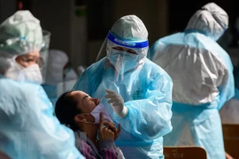 Nhân viên y tế lấy mẫu xét nghiệm COVID-19. (Ảnh: AFP/TTXVN)
