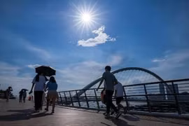 Người dân che ô tránh nắng trên đường phố tại tỉnh Phúc Kiến, Trung Quốc. (Ảnh: AFP/TTXVN)