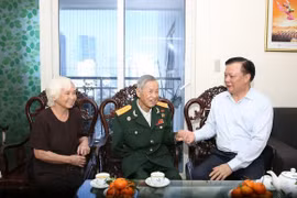 Bí thư Thành ủy Hà Nội Đinh Tiến Dũng thân mật thăm hỏi gia đình Anh hùng La Văn Cầu. (Ảnh: TTXVN)