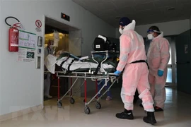Nhân viên y tế chuyển bệnh nhân COVID-19 vào bệnh viện ở Cremona, Italy. (Ảnh: AFP/TTXVN) 