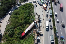 Chiếc xe container bị lật trên đường lên cầu Thanh Trì đã húc đổ cột biển báo, kéo đổ nghiêng cột khung biển báo hiệu, gây ùn tắc giao thông. (Ảnh: Huy Hùng/TTXVN) 