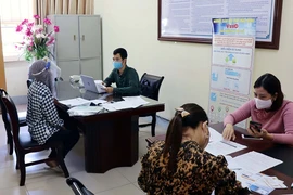 Người lao động đang được hướng dẫn làm thủ tục nhận hỗ trợ qua ứng dụng trực tuyến bảo hiểm xã hội số VssID. (Ảnh: Đại Nghĩa/TTXVN)