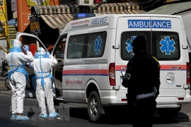 Nhân viên y tế chuyển bệnh nhân COVID-19 lên xe cứu thương tại Phnom Penh, Campuchia. (Ảnh: AFP/TTXVN) 