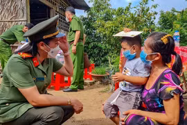 Nữ cán bộ Công an TP Cần Thơ trò chuyện với bé Nguyễn Huỳnh Gia Bảo (xã Tân Thới, huyện Phong Điền) có cha mất do COVID-19, mẹ bị F0 đang cách ly. (Ảnh: Thanh Liêm/TTXVN)